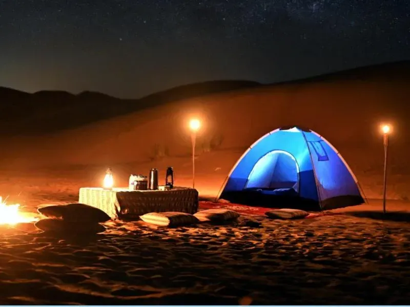 Overnight desert camp in Dubai with a tent and lanterns at night
